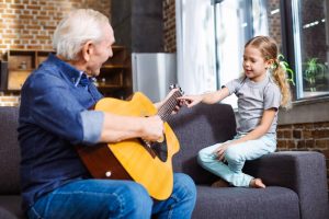 Starszy mężczyzna uczy dziecko gry na gitarze