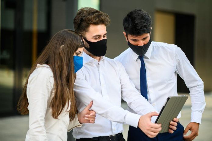 Biznesmen prezentujący swój pomysł na rozwijanie biznesu innym pracownikom w czasie pandemii
