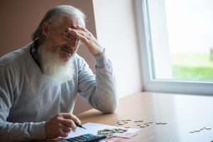 Zmartwiony senior liczy swoją emeryturę po waloryzacji